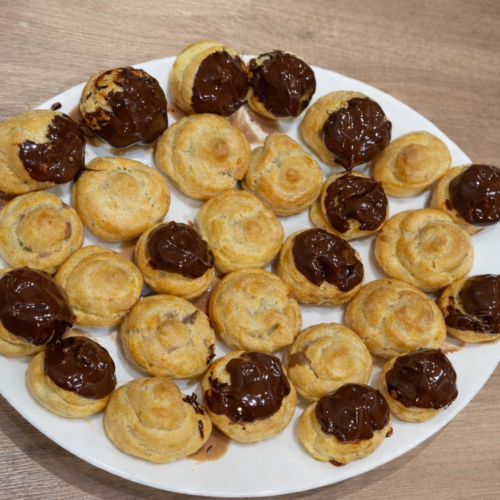 Piatto di bignè fatti in casa, preparati con pasta choux e farciti con crema pasticcera. Soffici, leggeri e perfetti come dessert o per un vassoio di dolci della tradizione.