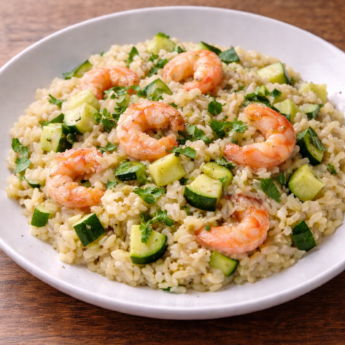 Risotto cremoso zucchine e gamberetti su piatto bianco