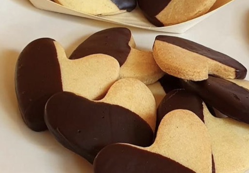 Biscotti a cuore ricoperti di cioccolato fondente su piatto bianco