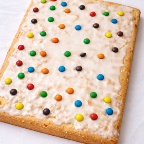 Torta in teglia con glassa al limone e confettini colorati su sfondo bianco