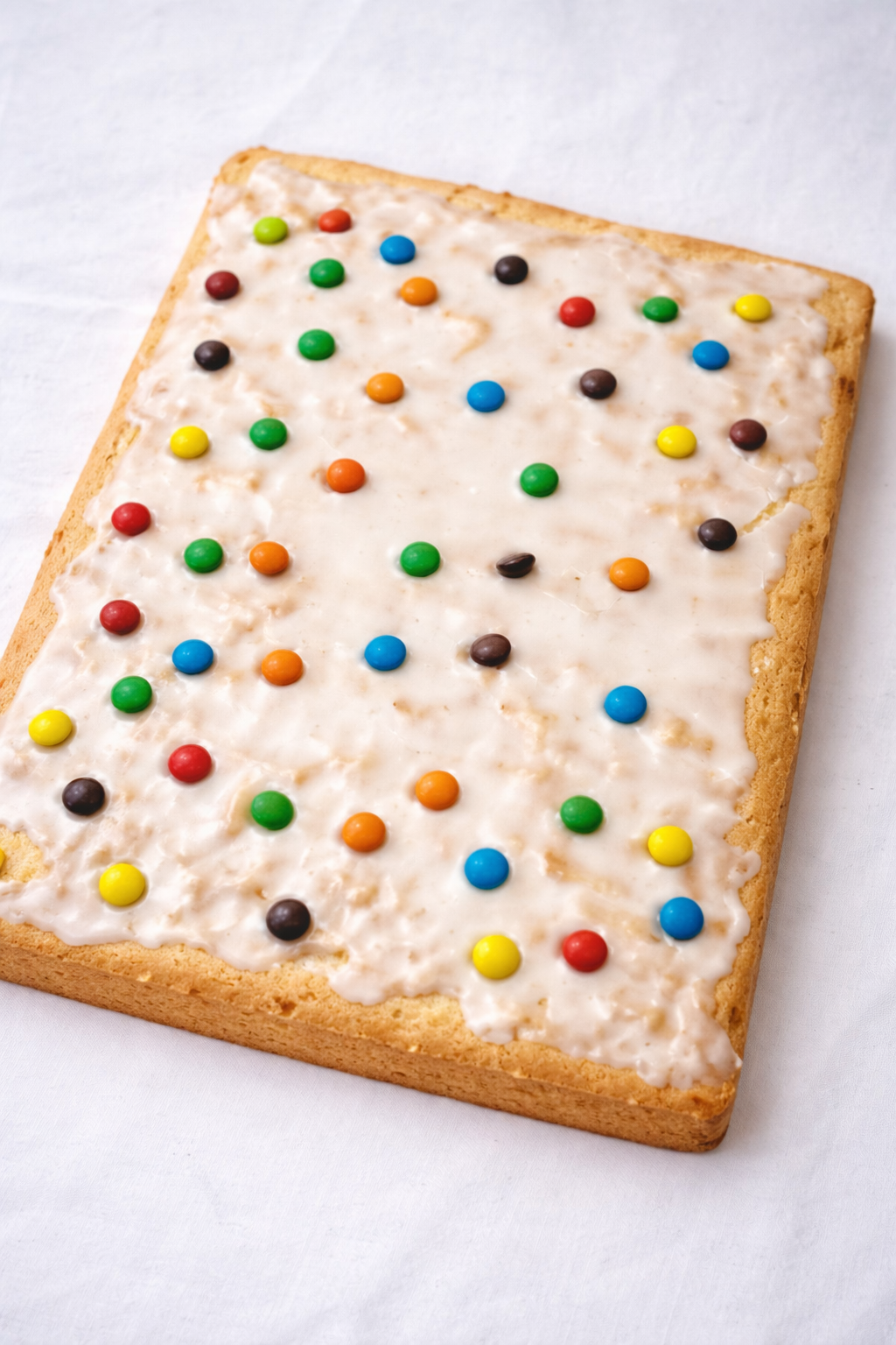 Torta in teglia con glassa al limone e confettini colorati su sfondo bianco