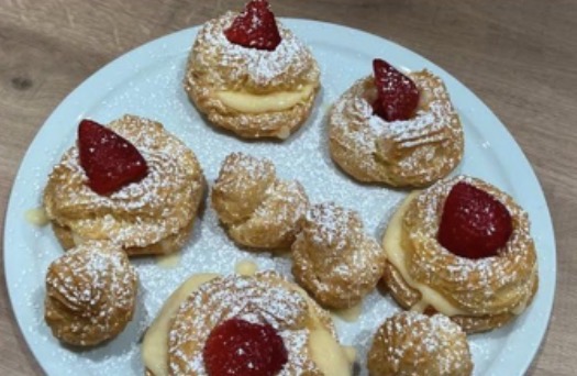 Zeppole di San Giuseppe con crema e fragole su piatto azzurro