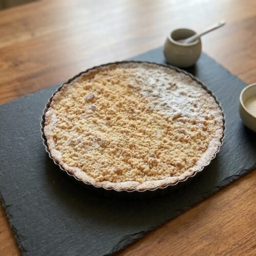 Crostata con Nutella sbriciolata dorata spolverata di zucchero a velo su ardesia
