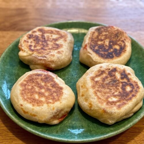 Pita ripiena in padella dorata con provola filante su piatto verde