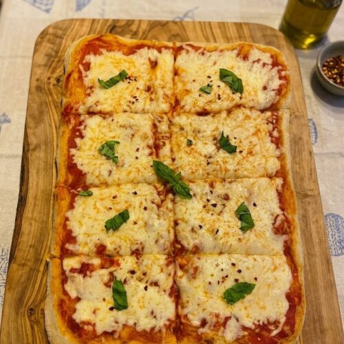Pizza in teglia fatta in casa con mozzarella filante e basilico fresco