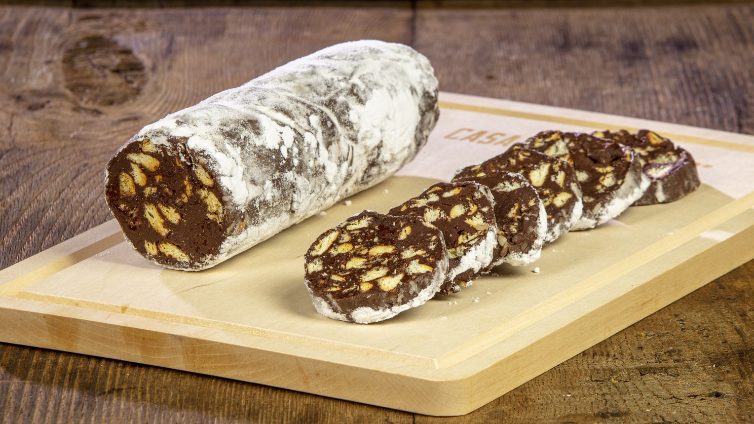 Salame di cioccolato affettato su tagliere con biscotti e zucchero a velo