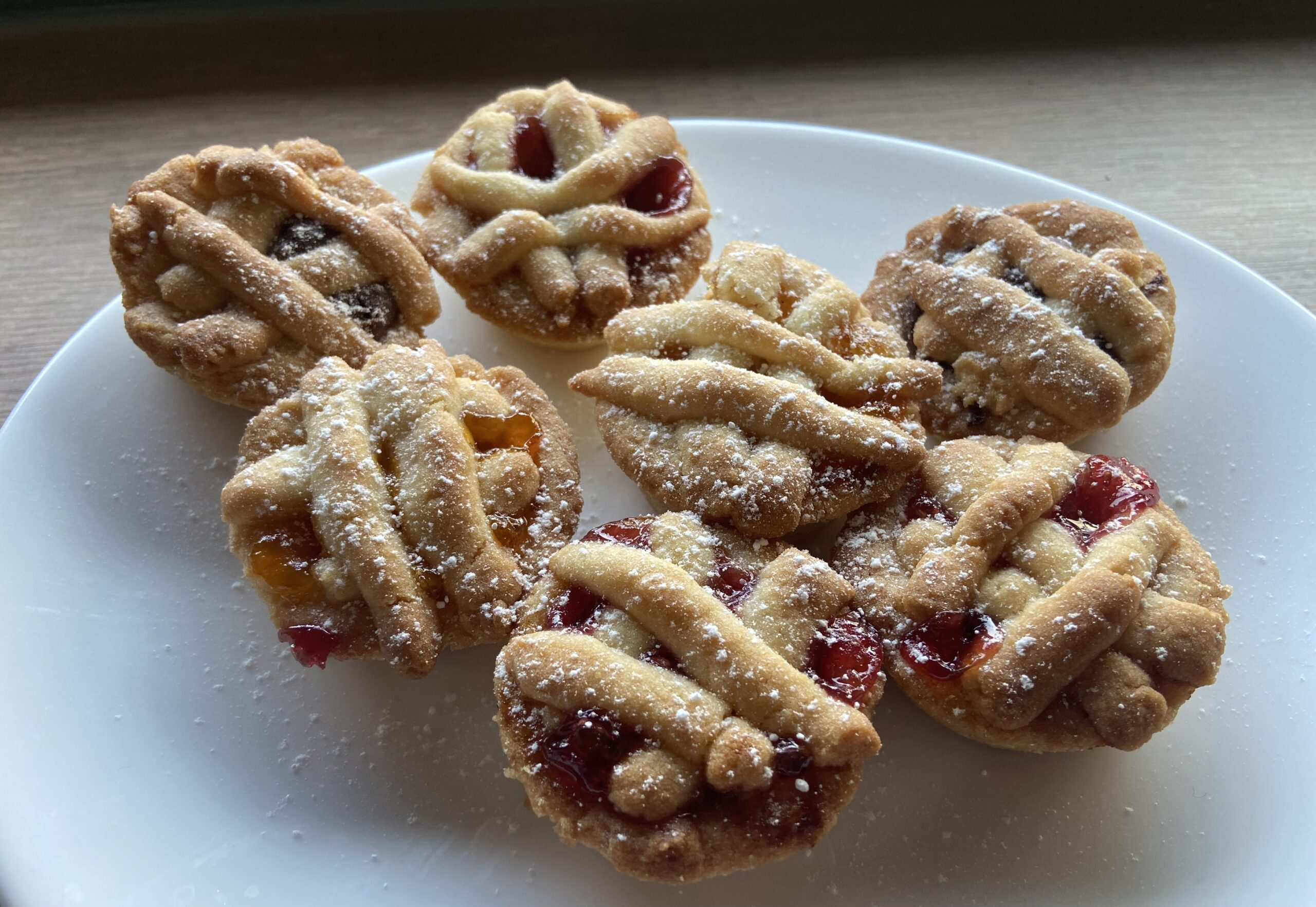 Crostatine con marmellata e zucchero a velo su piatto bianco